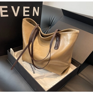 Detail view of khaki pleated leather tote bag with dark brown straps and zipper closure