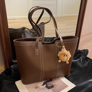 Brown leather tote bag with contrast white stitching and cute plush doll keychain