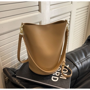 Detail of khaki leather bucket bag with adjustable strap and golden metal hardware details