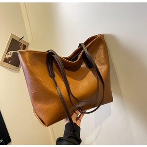 Detailed texture of caramel brown tote bag with wrinkled leather and dark straps