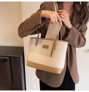 Détail d'un modèle insérant un téléphone dans le cabas en cuir bicolore minimaliste