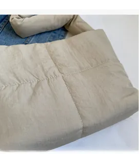Macro detail of beige quilted nylon puffer bag showing soft texture and stitching