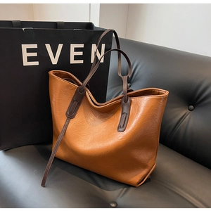 Close-up of brown vintage tote bag with premium leather texture on a black leather seat