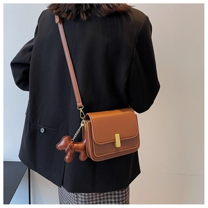 Détail du petit sac bandoulière marron avec pendentif chien et boucle en métal doré
