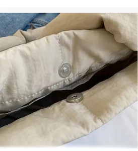 Close-up of the silver magnetic buckle hardware on a beige textured canvas tote bag
