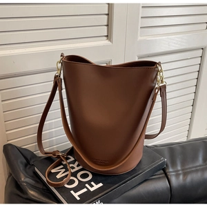 Detail of chocolate brown bucket bag with gold hardware on a Tom Ford lookbook