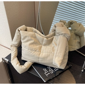 Close-up of quilted puffer tote bag with decorative knot detail on shoulder strap