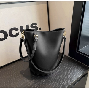 Detailed macro view of the black bucket bag showing the golden hardware and brand logo