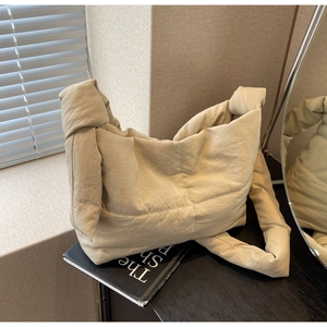 Detail of quilted beige tote bag showing soft padded texture and unique knotted shoulder strap