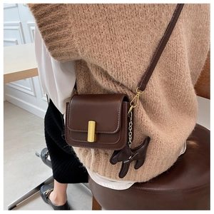 Close-up of brown vintage crossbody bag with gold buckle and cute puppy charm detail