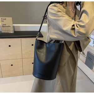 Detail of black large bucket bag with leather texture and engraved fashion lettering
