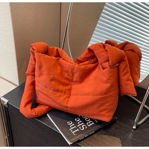 Detail of orange quilted tote bag with chunky knotted shoulder strap and padded texture