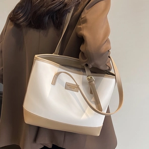 Grand sac cabas bicolore blanc et marron porté à l'épaule par un mannequin en manteau brun