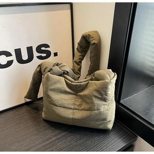 Detail of sage green quilted nylon tote bag featuring a soft padded texture and knot design