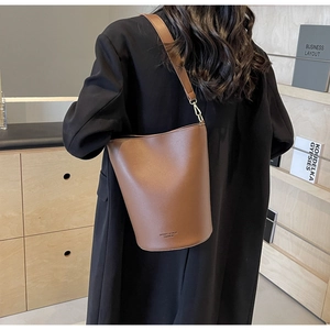 Detail view of large brown bucket bag with gold hardware and smooth matte texture finish