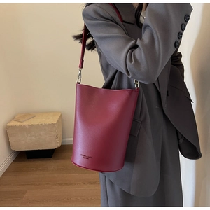 Macro shot of burgundy leather bucket bag showing the embossed brand logo on the base