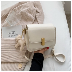 White leather crossbody bag with gold hardware and a cute beige dog charm accessory