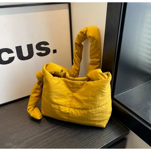 Detailed close-up of yellow quilted tote bag with side knot decor and puffy texture