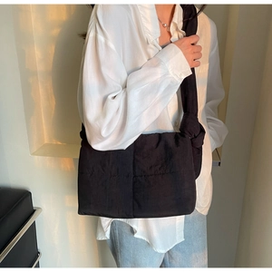 Close-up of black quilted puffer tote bag featuring stylish knot detail on padded shoulder strap