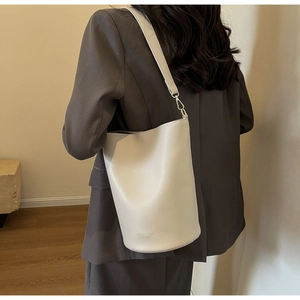 Detail view of light grey leather bucket bag with adjustable strap and chic fashion print