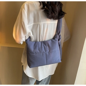 Close-up of Morandi blue quilted tote bag with large side knot detail worn over the shoulder