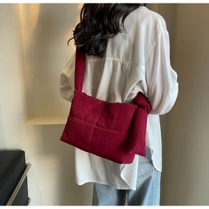 Detail of burgundy quilted tote bag featuring a decorative large shoulder strap knot