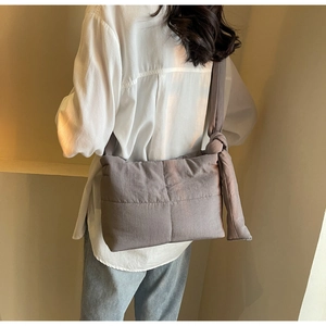 Detail of grey quilted shoulder bag showing padded texture and knotted strap design