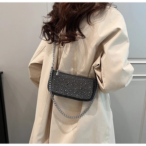 Detail of crossbody bag with silver rhinestones and elegant metal chain strap for women