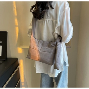 Detail of grey quilted canvas tote featuring large knot shoulder strap on model