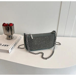 Detail of dark green sequined underarm bag with silver chain strap on white art deco pedestal