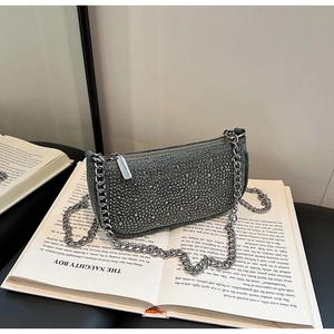 Close-up of rhinestone encrusted denim shoulder bag with a silver chain strap on a book