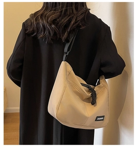 Detail of khaki nylon tote bag with black zipper and SHUNUO brand tag shown on model