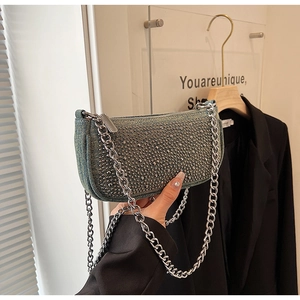 Detail of denim shoulder bag with silver studs and chunky metal chain strap