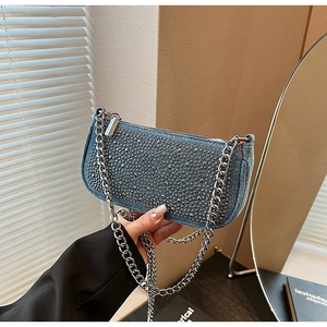 Detail of blue denim underarm bag with silver studs and thick metal chain strap