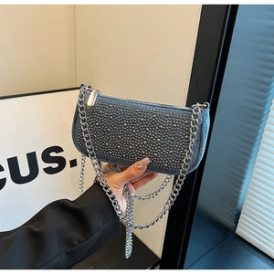 Detail of dark blue denim underarm bag with silver rivets and chunky metal chain strap