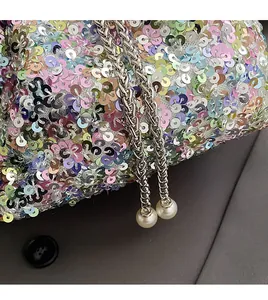 Détail de paillettes colorées, chaîne argentée et breloques perles sur un sac seau chic