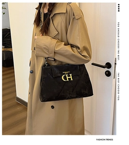 Détail du sac matelassé noir avec chaîne, logo doré et texture en cuir élégant