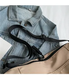 Macro detail of khaki nylon tote bag featuring adjustable black shoulder strap and zipper