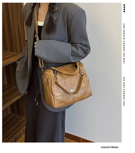 Dettaglio della borsa marrone vintage con cuciture trapuntate e catena indossata da modella