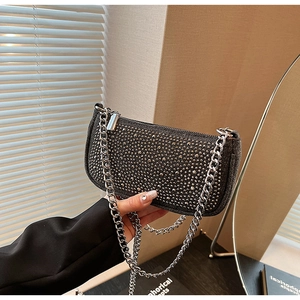 Detail of a black studded underarm bag with silver chain strap and metal rivets