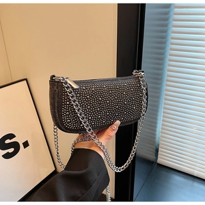 Detail of black underarm bag featuring silver studs and a heavy chain shoulder strap