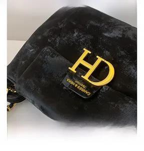 Vue détaillée de la texture en cuir noir matelassé et du logo HD doré sur un sac à main