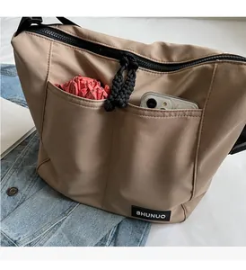 Detail view of khaki nylon tote bag featuring functional front pockets with a phone and umbrella