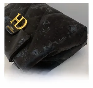 Gros plan du sac à bandoulière matelassé noir avec fermoir H doré et chaîne