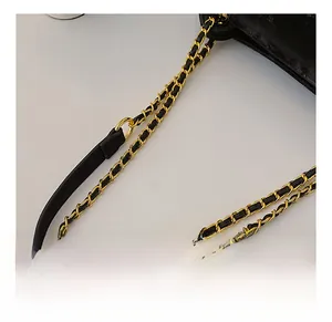 Détail de la chaîne en métal doré entrelacée d'un bracelet en cuir noir pour sac à main