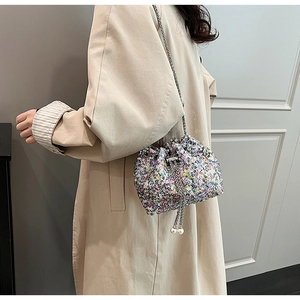 Détail du sac seau à paillettes avec bandoulière chaîne et cordon à perles décoratif