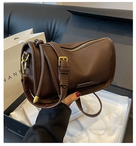 Detail of dark brown pebble leather Boston bag with gold hardware and side logo
