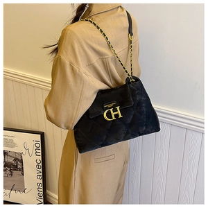 Détail d'un sac bandoulière noir matelassé avec logo CH doré et chaîne sur un mannequin