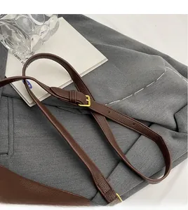 Detail of dark brown lychee leather shoulder strap with golden adjustable buckle