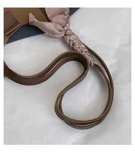 Close-up of brown textured leather shoulder strap wrapped with a decorative silk scarf